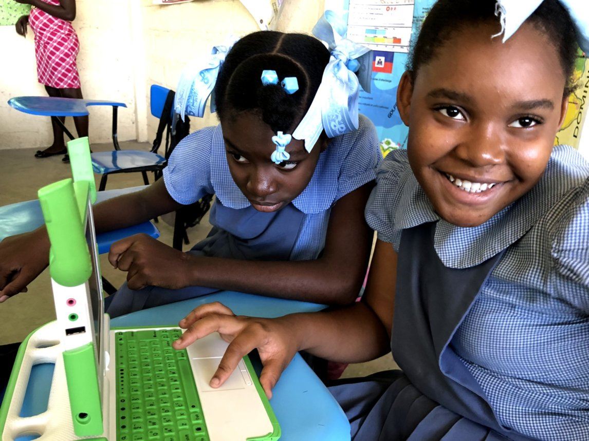 Two Haitian schoolgirls working on a laptop