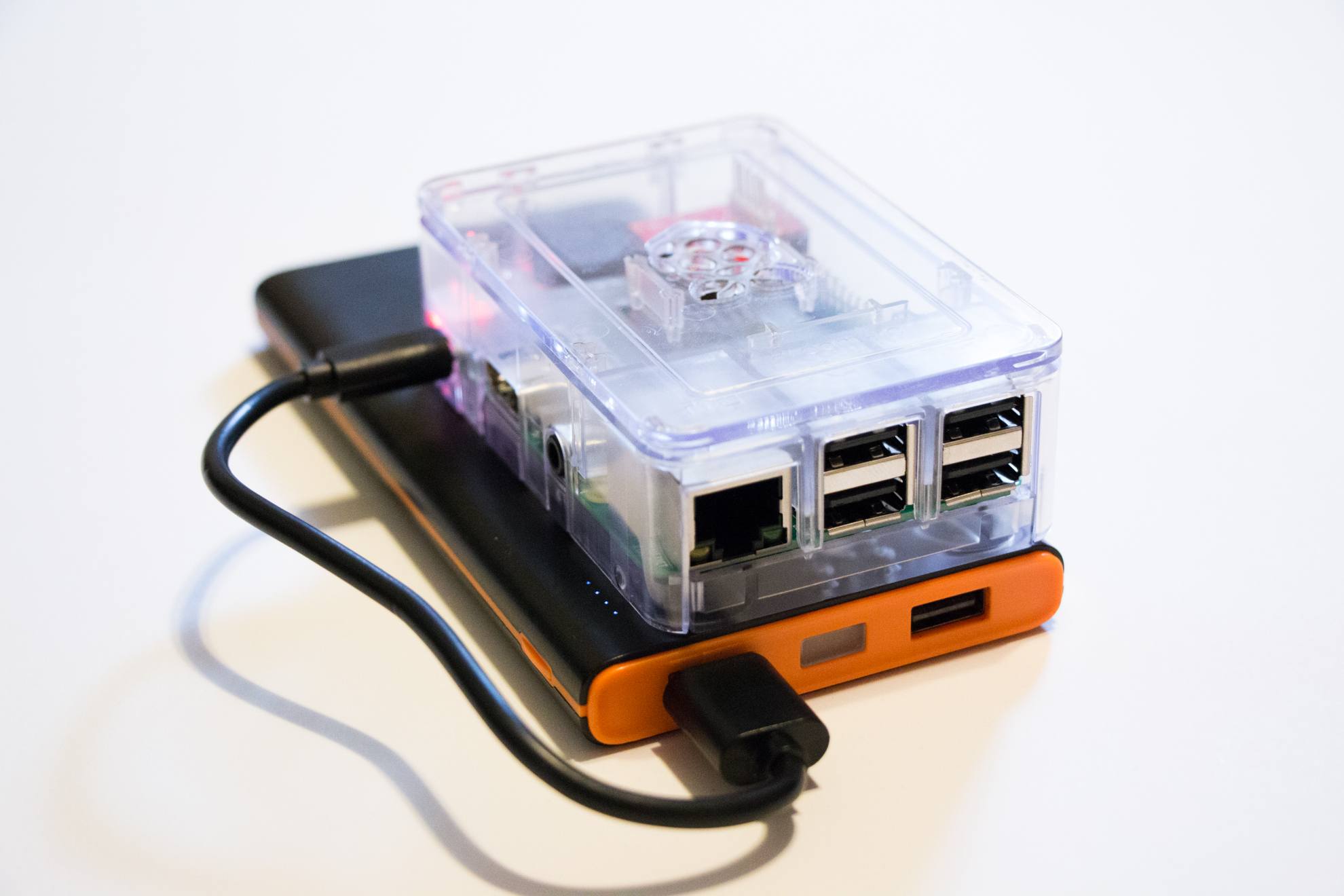 Raspberry Pi in a clear case, connected to an orange battery bank